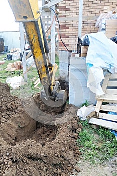 The excavator digging a trench near a cable house for a small bucket