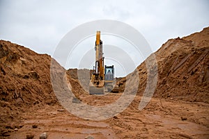 Excavator digs a large trench for pipe laying. Backhoe during earthmoving at construction site. Earth-moving heavy equipment