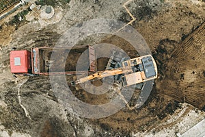 Excavator digs pit foundation. Earthwork in excavation in construction site, aerial top view