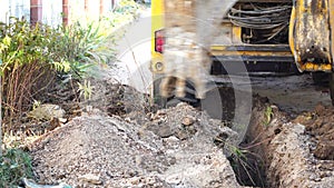 Excavator digs a trench to lay pipes. Close up of an excavator digging a deep trench. An excavator digs a trench in the