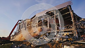 Excavator dismantles destroyed hockey stadium in evening