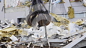 Excavator dismantles rubble at demolition site of stadium