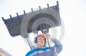 Excavator driver in hard hat stands at construction equipment, concept industrial man portrait