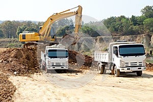 Excavator and dump truck tipper in construction site