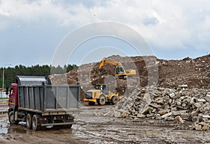 Excavator, dump truck and wheel loader at landfill for disposal of construction waste and concrete crushing. Recycling concrete