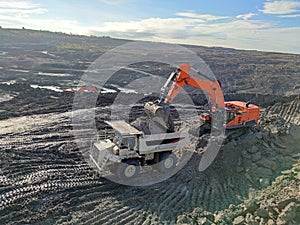 Excavator and dump truck working in coal mine area.