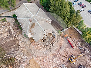 Excavator and dump truck working at the demolition of an old derelict building