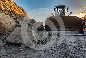 Excavator at dusk in a stone quarry