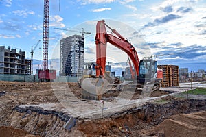 Excavator during earthmoving at construction site on bluue sky background. Ð¡onstruction machinery for excavating. Tower cranes