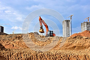 Excavator during earthmoving at construction site. Ð¡onstruction machinery for excavating. Tower cranes lifting a concrete bucket