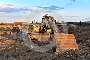 Excavator during earthmoving at construction site on sunset background. Ð¡onstruction machinery for excavating.