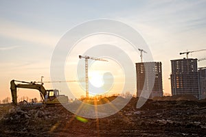 Excavator during earthmoving at construction site on sunset background. Ð¡onstruction machinery for excavating. Small roughness