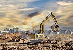 Excavator during earthmoving work at construction site on sunset background. Backhoe digging ground for foundation pit. Open pit