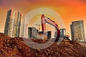 Excavator during earthmoving work at construction site on sunset background. Backhoe digging ground for foundation pit. Tower