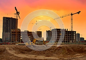 Excavator during earthmoving work at construction site on sunset background. Backhoe digging ground for foundation pit. Tower