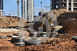 Excavator on earthwork during the laying of pipes of the heating system to a new residential building at the construction site.