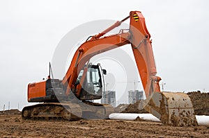 Excavator during earthworks at construction site. Backhoe digging the ground for the foundation and for laying sewer pipes
