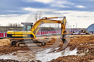 Excavator on earthworks at construction site. Backhoe on foundation work and road construction. Heavy machinery and construction