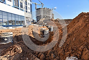 Excavator on earthworks for laying heating pipes and stormwater in trench. Installing concrete wells, Ñhambers, manholes near new