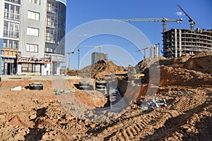 Excavator on earthworks for laying heating pipes and stormwater in trench. Installing concrete wells, Ñhambers, manholes near new