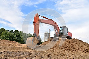 Excavator during excavation aond road construction works at construction site on sunset background. Backhoe on foundation work in