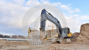 Excavator during excavation at construction site. Backhoe on foundation work in sand pit. Groundworks, site levelling, photo