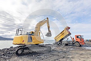 The excavator is excavation loading to truck. Construction equipment being used to dig up rocky ground.