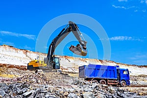 excavator extracts clay and loads into blue truck