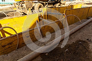 Excavator filling deep excavation supported by trench box with pipe bedding pea gravel during installation of drainage pipe