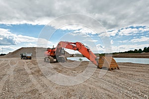 Excavator in a gravel pit with cloudy sky