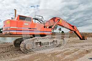 Excavator in a gravel pit with cloudy sky