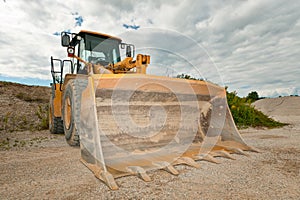 Excavator in a gravel pit with cloudy sky with a big shovel