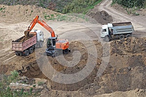 Excavator grows the pit and loads the dump truck