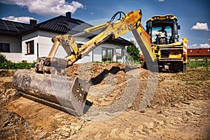 Excavator at house construction site - digging foundations for modern house