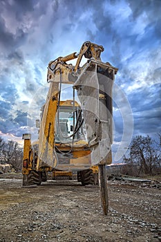 Excavator with hydraulic breaker hammer for the destruction of concrete and hard rock at the construction site or quarry.