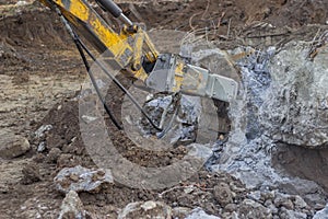 Excavator with hydraulic hammer breaking concrete 2