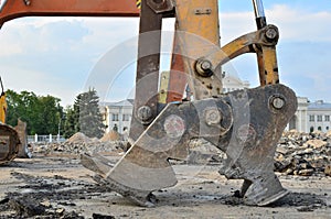 Excavator with hydraulic shears breaks asphalt on a construction site. Hydraulic shear crusher pulverizer for excavator.