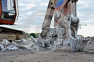 Excavator with hydraulic shears for cutting and crumbles demolition concrete and asphalt at construction site. Hydraulic breaker.