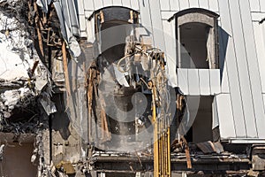 Excavator with hydraulic shears dismantles the roof and the roof of the building