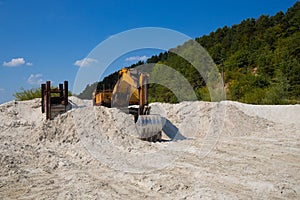 Excavator industrial equipment transport in warming wasteland hills sand on outskirts polluted environment area