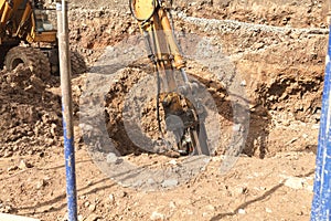 Excavator with a jackhammer breaks rocks in the ground