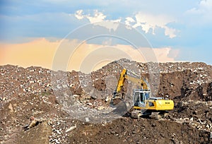 Excavator at landfill for the disposal of construction waste. Backhoe digs gravel and concrete crushing. Recycling old concrete