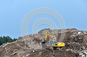 Excavator at landfill for the disposal of construction waste. Backhoe digs gravel and concrete crushing. Recycling old concrete