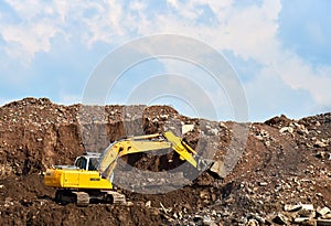 Excavator at landfill for the disposal of construction waste. Backhoe digs gravel and concrete crushing. Recycling old concrete