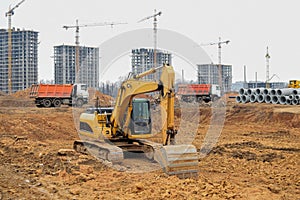 Excavator with a large iron bucket on a construction site during road works. Backhoe dig the ground for the foundation, laying