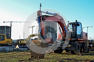 Excavator with a large iron bucket on a construction site during road works. Backhoe dig the ground for the foundation, laying