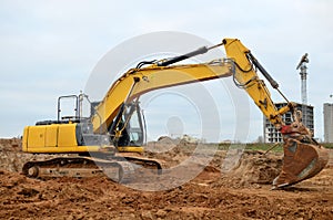 Excavator with a large iron bucket on a construction site during road works. Backhoe dig the ground for the foundation, laying