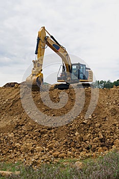 Excavator on large pile of dirt
