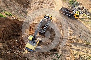 Excavator load the sand into dump truck. Aerial view of an backhoe on earthworks. Open pit development and sand mining. Loader