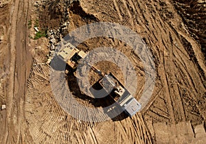 Excavator load the sand into dump truck. Aerial view of an backhoe on earthworks. Open pit development and sand mining. Loader